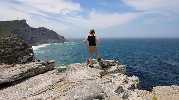 Magnus standing on a cliff at the Cape of Good Hope, South Africa, looking out over the ocean.
